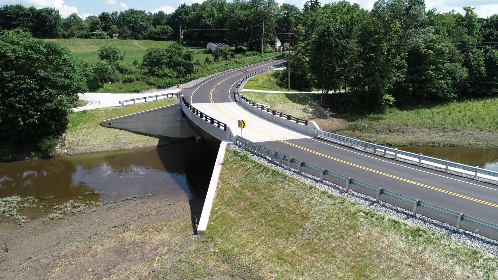 Aerial view of a completed bridge and roadway over a stream